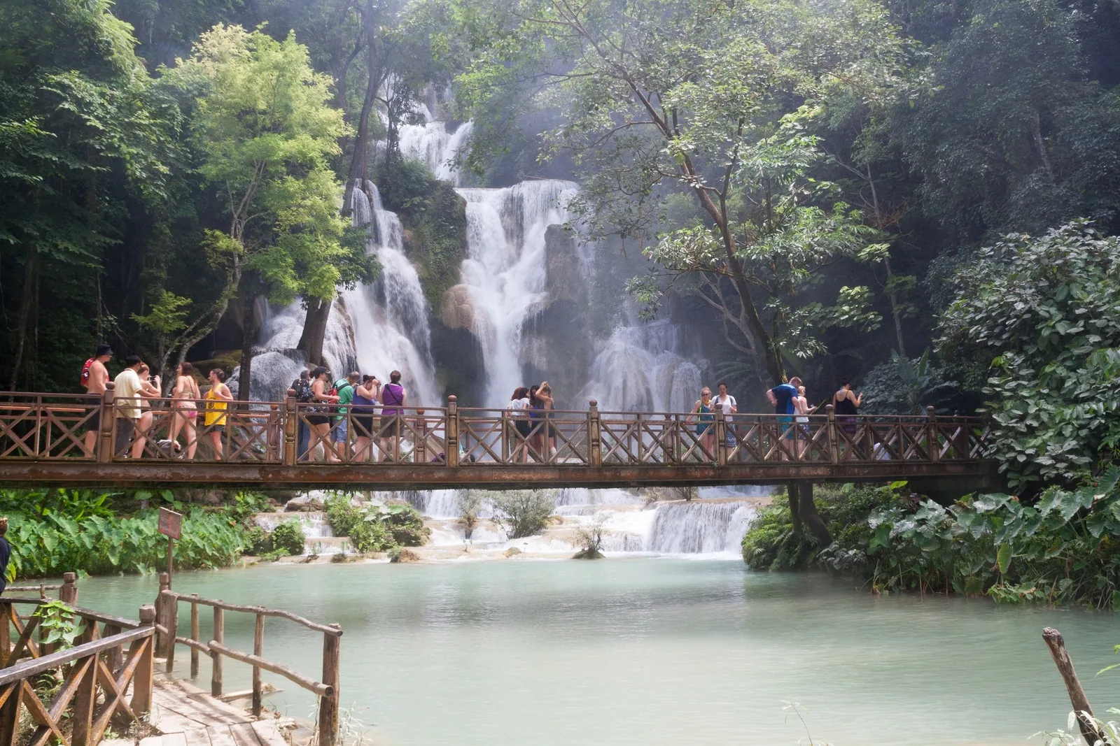 Tourists cross a wooden bridge in front of Kuang Si Falls near Luang Prabang, Laos.