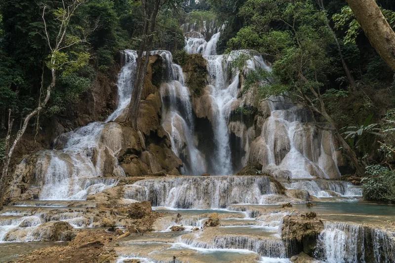 Multi-tiered limestone cascades of Kuang Si Falls flow over turquoise pools near Luang Prabang. Multi-tiered limestone cascades of Kuang Si Falls flow over turquoise pools near Luang Prabang.