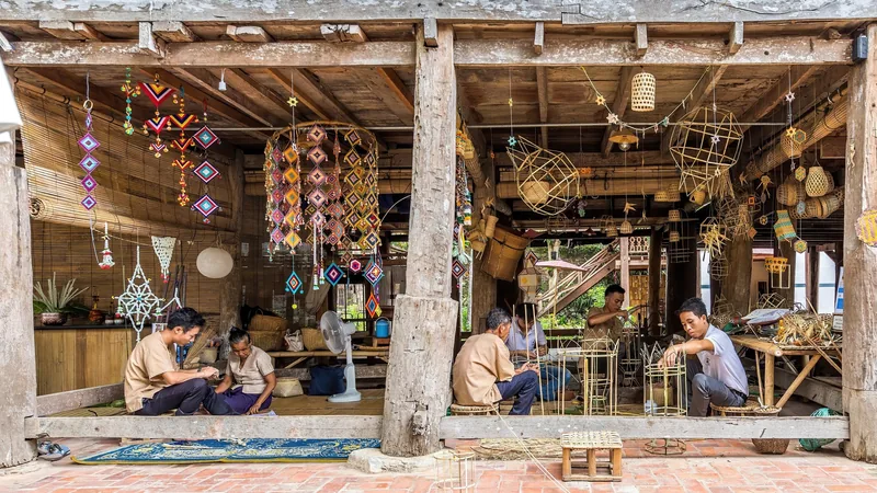 Craftsmen weave bamboo baskets and lanterns under a wooden pavilion decorated with colorful hangings in Luang Prabang.