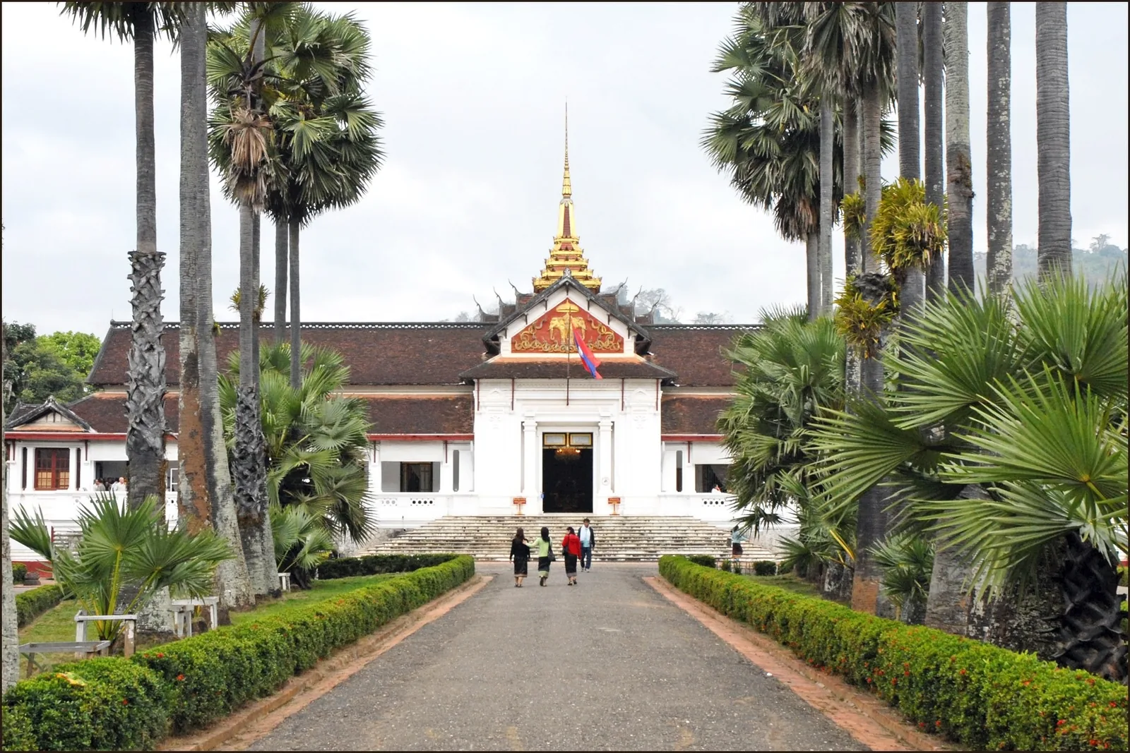 A palm-lined avenue leads to the golden-spired former Royal Palace in Luang Prabang.