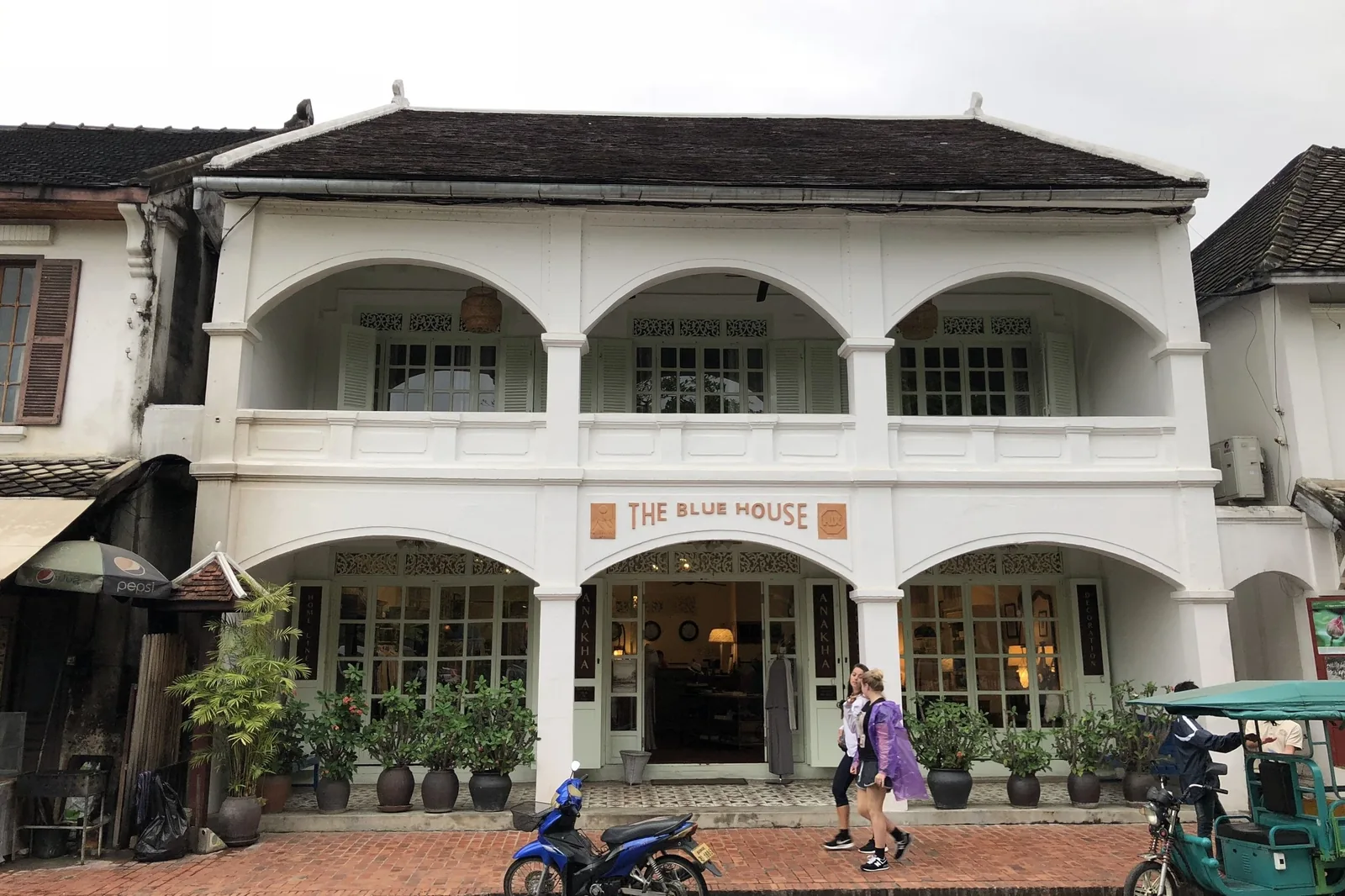 A colonial-era white building with arched balconies houses a shop called The Blue House in Luang Prabang. A colonial-era white building with arched balconies houses a shop called The Blue House in Luang Prabang.