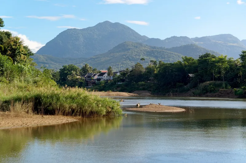 The Nam Khan River winds past sandy banks and forested mountains near Luang Prabang, Laos.