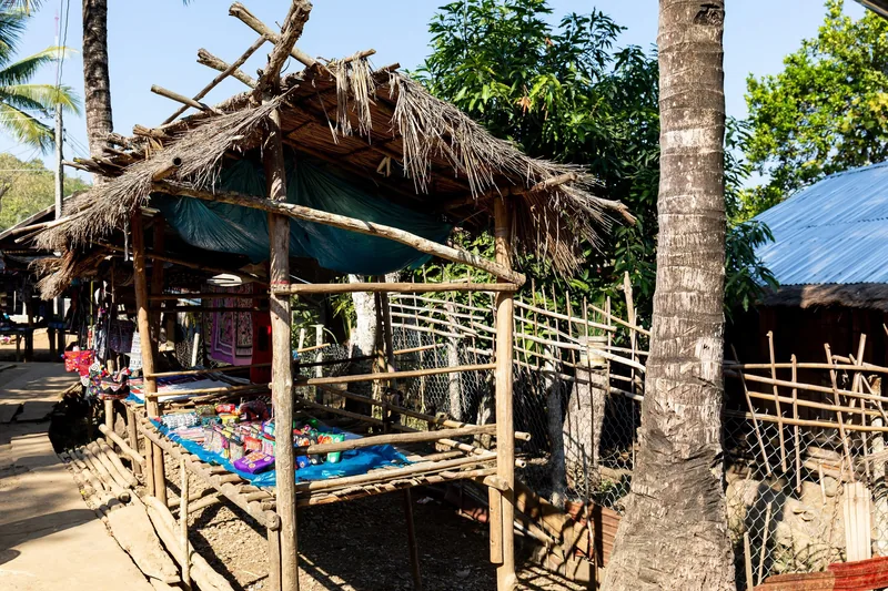 A thatched-roof souvenir stall displays handicrafts on a wooden table in a Luang Prabang village. A thatched-roof souvenir stall displays handicrafts on a wooden table in a Luang Prabang village.