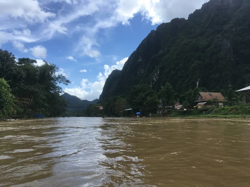 Muddy waters of the Nam Song River flow beneath limestone karsts near Vang Vieng, Laos.