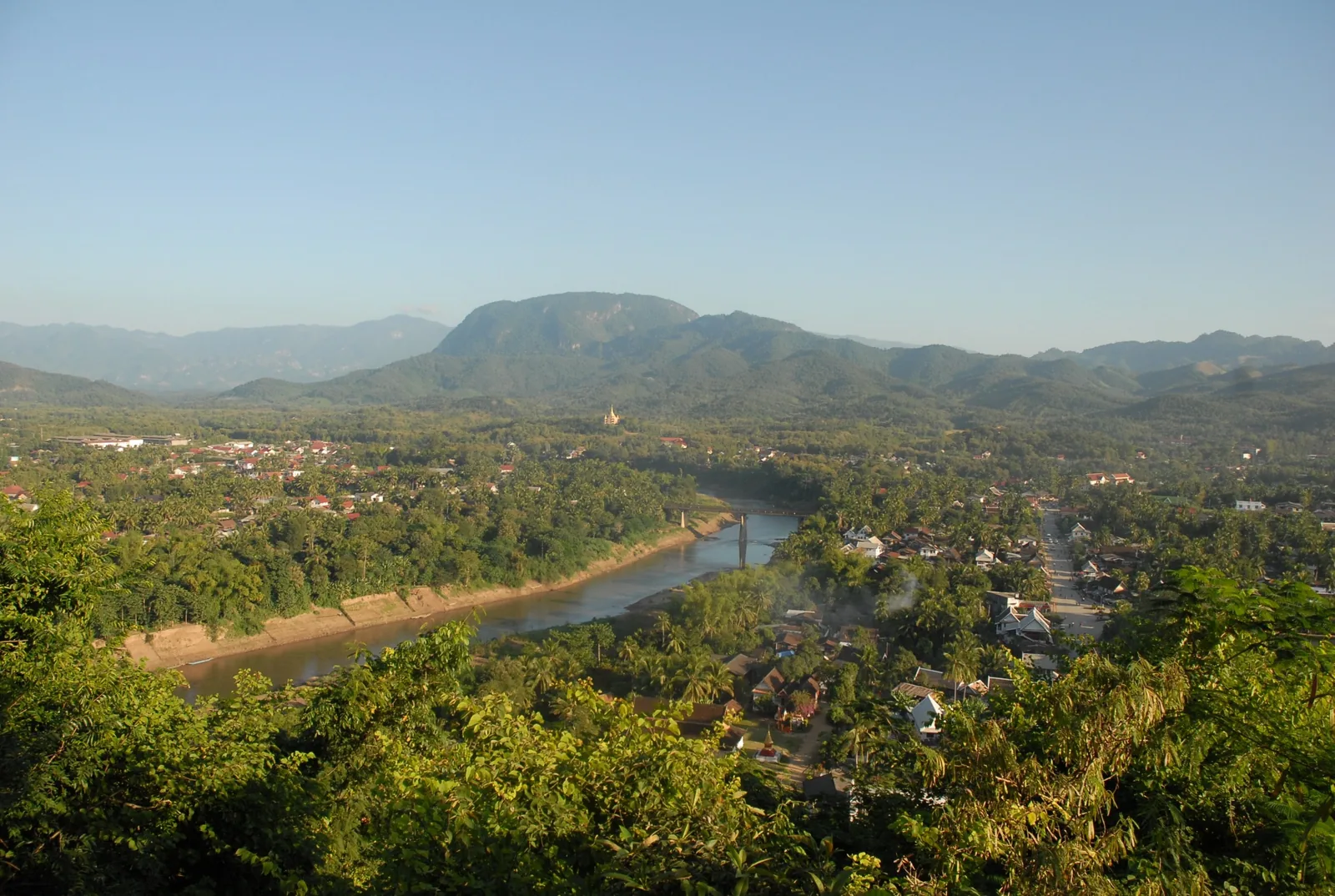 Aerial view from Mount Phousi over the Nam Khan river, town rooftops and forested hills in Luang Prabang.